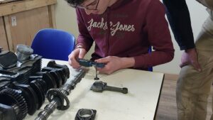 Stagiaire en cours d'apprentissage avec Samuel pendant le stage sur un moteur de moto